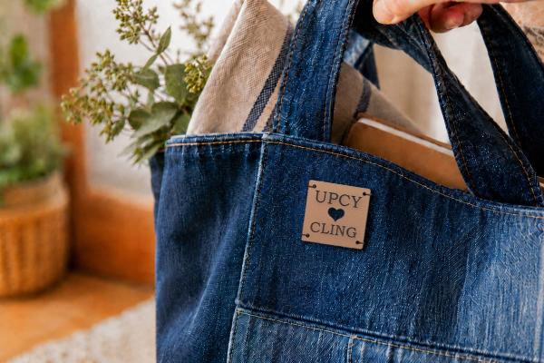 Etiqueta cuadrada de cuero de cactus claro con «UPCYCLING» y corazón troquelado en bolso vaquero.
