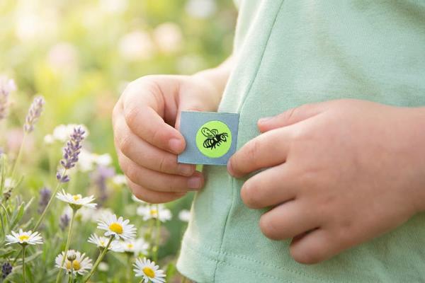 Etiqueta azul clara con abeja cosida en la costura de una prenda infantil
