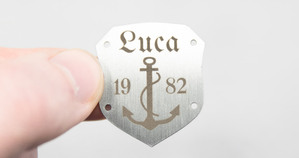 Etiqueta de metal con forma de escudo, acero inoxidable cepillado